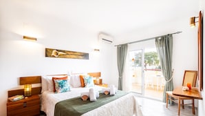 A hotel room with a bed, a nightstand, a table, and a view of the outdoors. - Villa w/ Heatable Pool and BBQ in Galé (Albufeira)