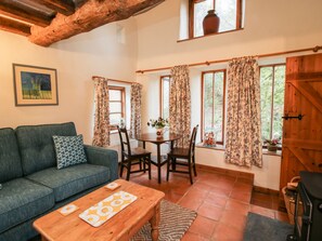 A cozy living room with a sofa, a wooden coffee table, and a dining area with a table and chairs.