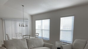 A modern living room with a white sofa, a coffee table, and a ceiling fan. - 2BR/2BA Patio Villa in the Village of DeLuna (The Villages)