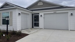 A single-story house with a garage, a front door, and a small porch area. - 2BR/2BA Patio Villa in the Village of DeLuna (The Villages)