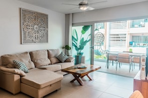 A modern living room with a sofa, coffee table, and a large window. - Beach getaway for amazing vacation in Punta Cana (Punta Cana)