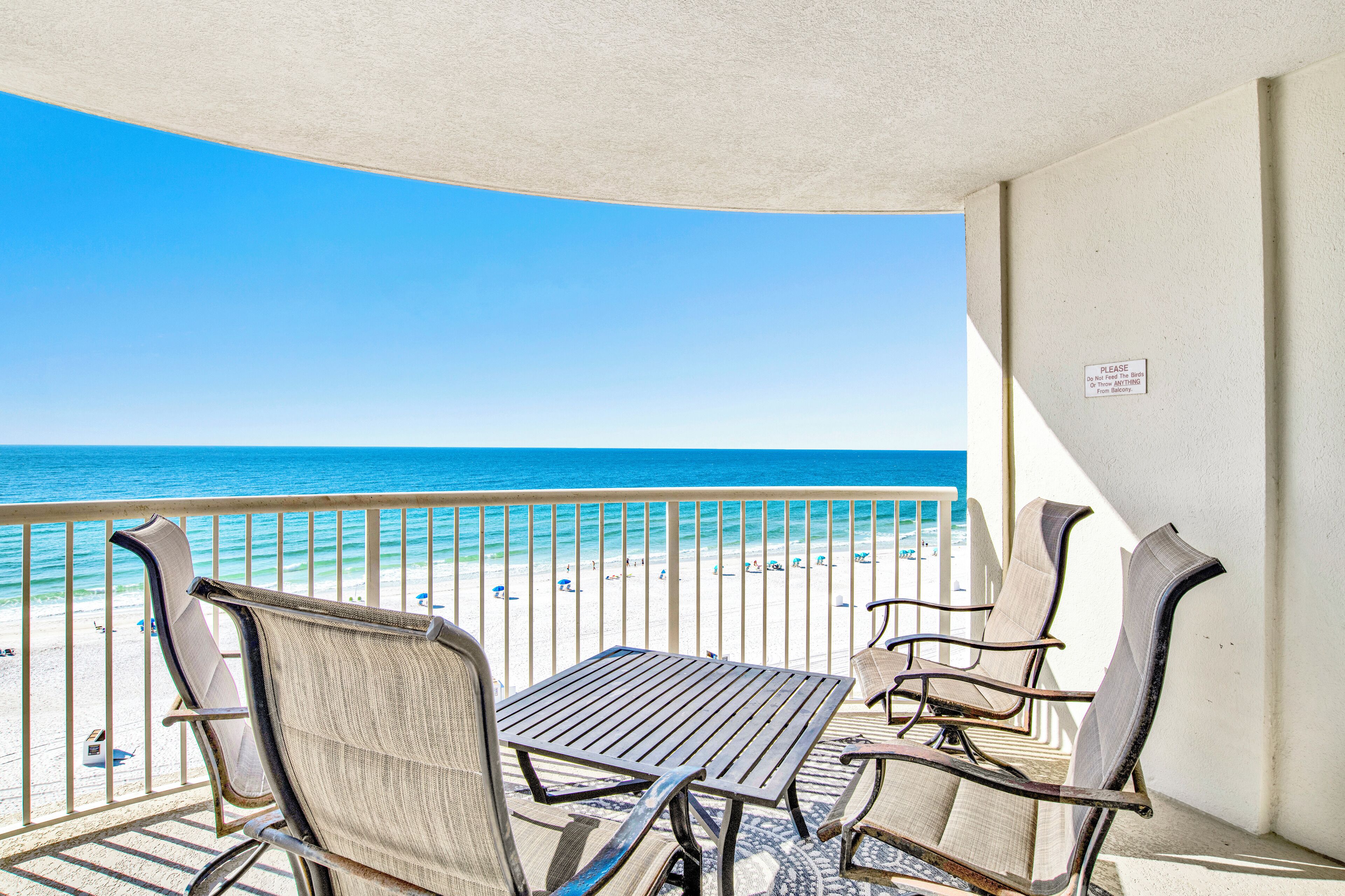 A balcony with a view of the beach and ocean.