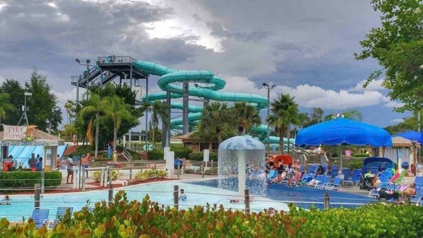 A water park with a large water slide, a pool, and lounge areas.