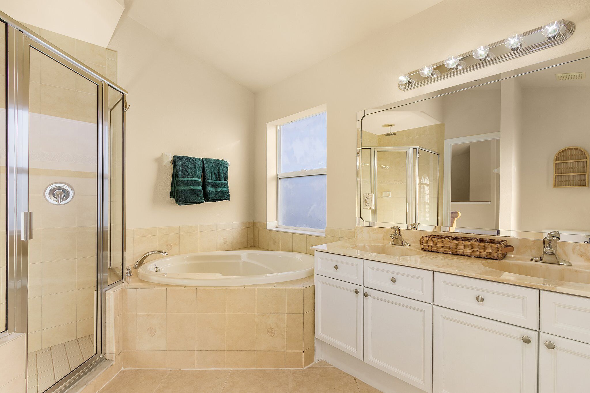 Une salle de bain dotée d’une douche à parois de verre, d’une baignoire sur pieds et d’un meuble-lavabo avec un miroir et des luminaires.