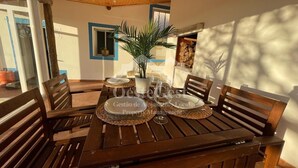 Une table de salle à manger en bois, mise avec des assiettes, des verres et une plante en pot.