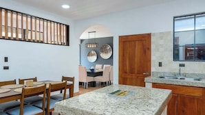 Una cocina moderna con encimeras de granito, armarios de madera y un comedor con mesa y sillas.