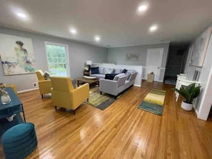 Un salón amplio con suelo de madera, un sofá, sillones y una mesa de centro.