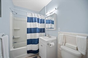 A bathroom with a bathtub, a sink, a toilet, and a shower curtain. - Cozy Coastal Getaway - Steps to Beach (Wrightsville Beach)
