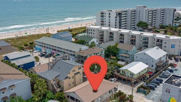 Zona residencial costera con edificios de varios pisos, una playa y un estacionamiento.