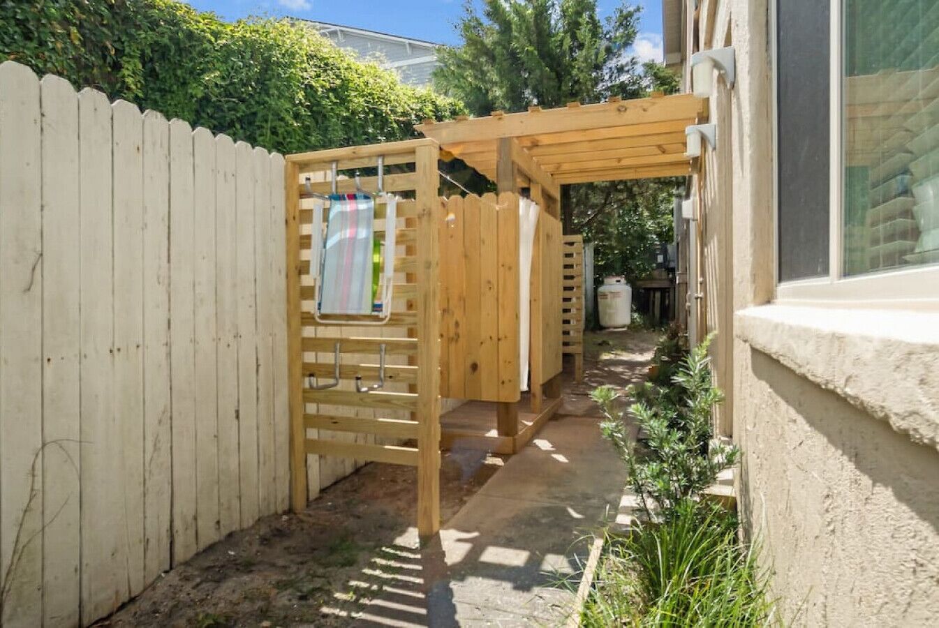 A wooden pergola with a clothesline in a backyard.
