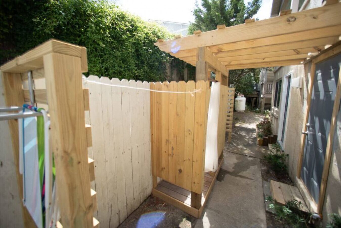 En have med træhegn, træbænk og en pergola.