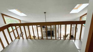 A spacious room with a high ceiling, skylights, and a view of a fireplace. - Lake Harmony, 4BR, Lake Access, Kayak, Woods, Air Hockey, New Water Treat System (Lake Harmony)