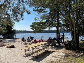 A beach with picnic tables and people relaxing. - Lake Harmony, 4BR, Lake Access, Kayak, Woods, Air Hockey, New Water Treat System (Lake Harmony)