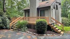 A two-story house with a wooden deck and stairs leading to a front door. - Lake Harmony, 4BR, Lake Access, Kayak, Woods, Air Hockey, New Water Treat System (Lake Harmony)