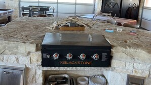 A stone-built outdoor kitchen with a Blackstone grill, a table with chairs, and a covered area with a table and chairs. - Bunkhouse in Texas ranch country (Guthrie)