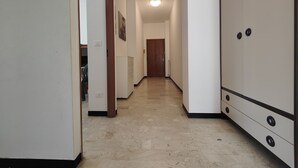 A hallway with a white wardrobe, a wooden door at the end, and a radiator on the wall.