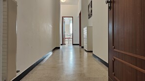 A hallway with a marble floor, white walls, and a wooden door on the right.