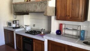 A kitchen with a gas stove, microwave, toaster, and a coffee maker.