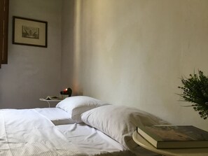 A bedroom with a bed, a bedside table with a lamp, a framed picture on the wall, and a potted plant. - Bargello Apartment - Two Bedroom Apartment, Sleeps 4 (Firenze)