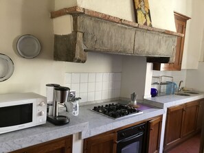 A kitchen with a white microwave, coffee maker, gas stove, and wooden cabinets.