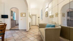A hallway with a sofa, a TV, and framed pictures on the walls. - Terme Apartment - Two Bedroom Apartment, Sleeps 4 (Firenze)
