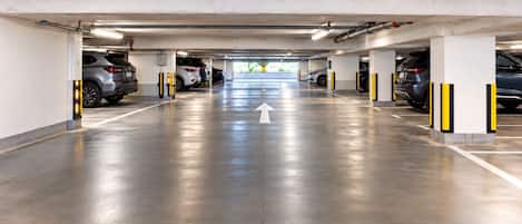 Garagem de estacionamento em vários níveis com uma seta direcional no chão, vários espaços de estacionamento e o logotipo da Spice Vacation Rentals.