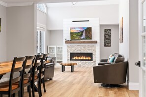 A modern living room with a fireplace, a dining area, and a comfortable seating arrangement.