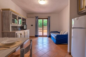 A compact kitchen with a dining area, a bed, and a view through a glass door.