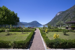 A paved pathway leading to a lake with mountains in the background. - Villa Apartments - Porto Letizia (Porlezza)