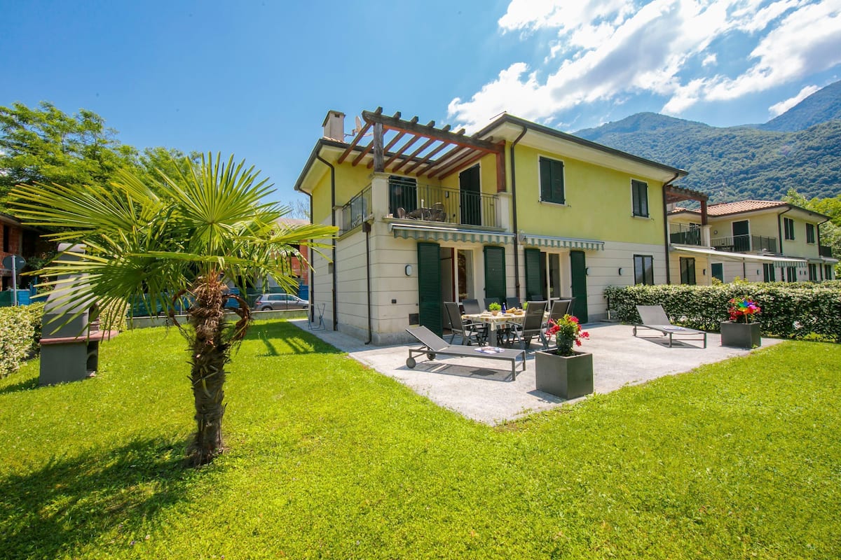 A two-story building with a balcony, a patio area with outdoor furniture, and a well-maintained lawn.