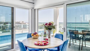 Un comedor con una mesa dispuesta para dos personas, un cuenco de fruta, una botella de champán y un jarrón de flores.