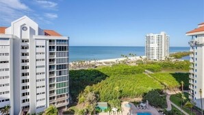 A high-rise hotel with a pool area, surrounded by lush greenery and a view of the ocean. - Beautiful Gulf views from this 9th floor condo - CL0902 (Naples)