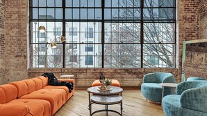 Una habitación moderna con un ventanal grande, un sofá, sillas y una mesita.