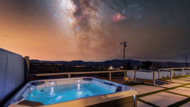 A hot tub with a clear night sky view, surrounded by a deck and a railing. - Boho🎨 Haus✦NearPark✦Views✦HotTub✦🎮Den✦🔥Pit✦Ev🔋 (Joshua Tree)