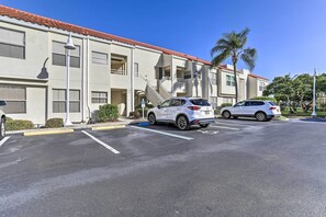 A parking lot with two white cars, a building with a red-tiled roof, and a palm tree. - 4 Mi to St Pete Beach! Family Condo w/ Pool Access (St. Petersburg)