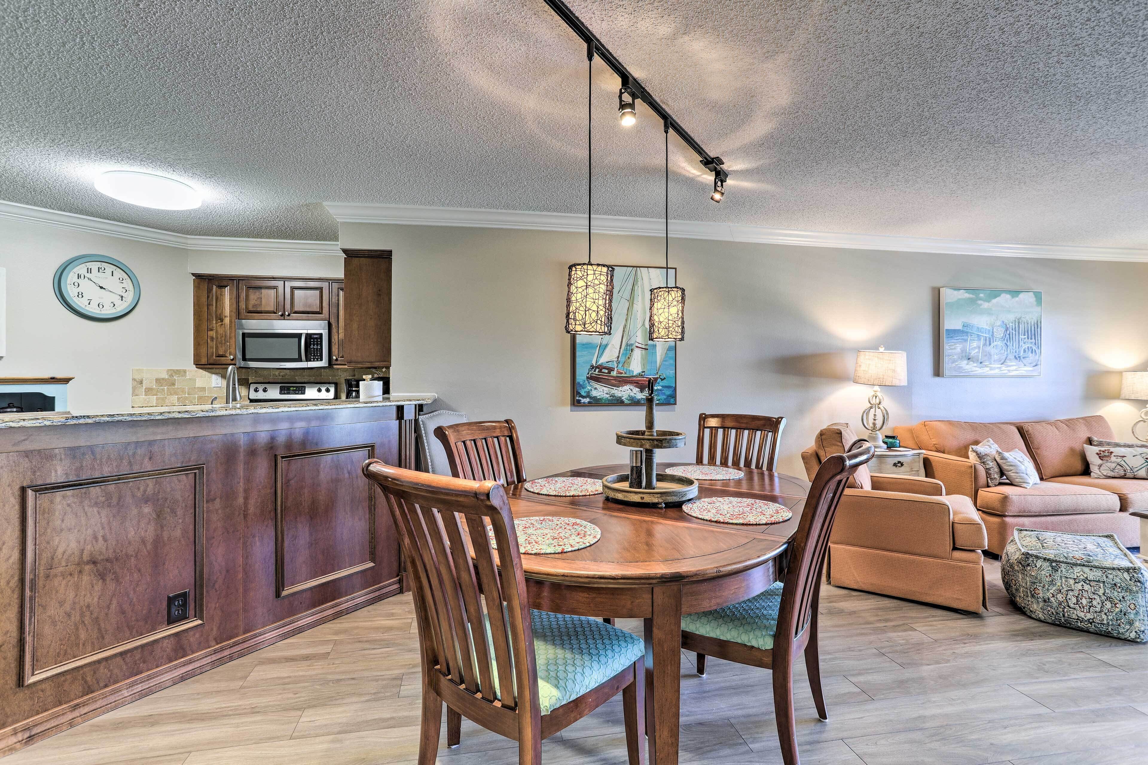 Una cocina moderna con microondas, armarios de madera y un comedor con mesa redonda y sillas.