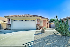 A residential garage with a white door, a small cactus in the driveway, and a clear blue sky.