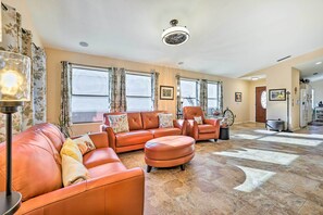 A spacious living room with a large sectional sofa, a round ottoman, and a floor lamp.