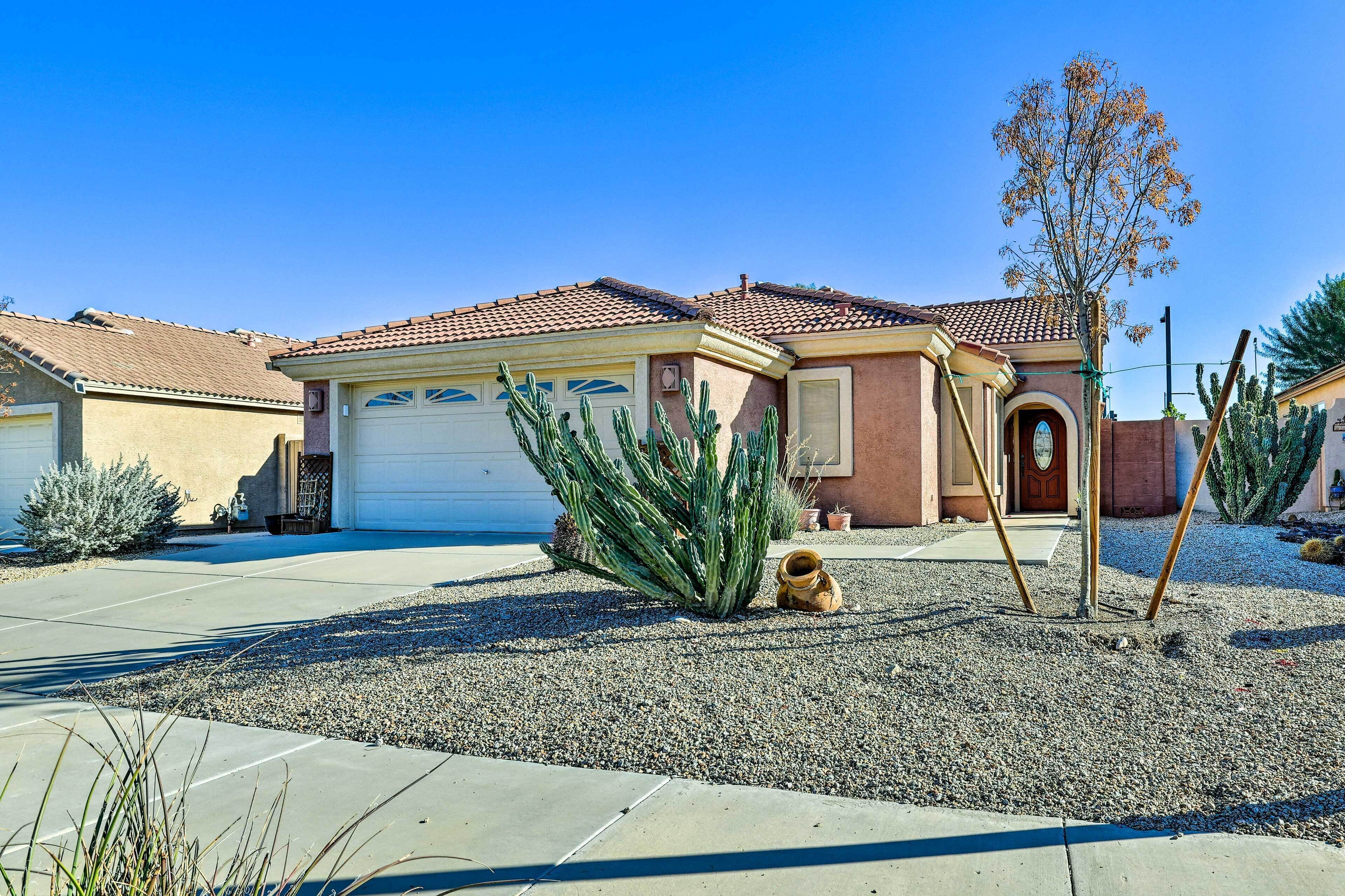 A residential house with a garage, a small garden with cacti, and a clear blue sky.