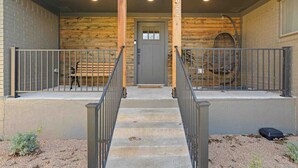 A wooden exterior with a gray door, concrete steps, and metal railings. - Serene Getaway Near Baylor and Magnolia Perfect for Relaxation and Exploration (Waco)