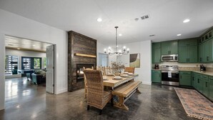 Una cocina amplia con gabinetes verdes, horno empotrado y comedor con mesa y sillas de madera.