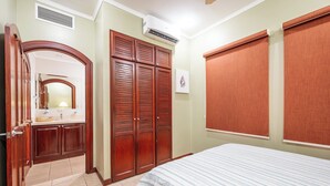 Un dormitorio con cama, armario, espejo y ventana con persiana.