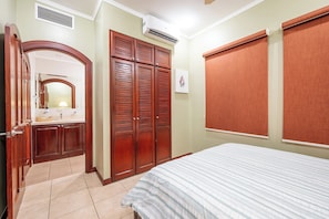 A bedroom with a bed, a wardrobe, a mirror, and a window with a blind.