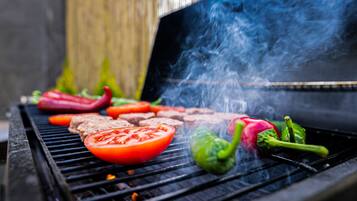 Un barbecue avec divers légumes et morceaux de viande en train de cuire.