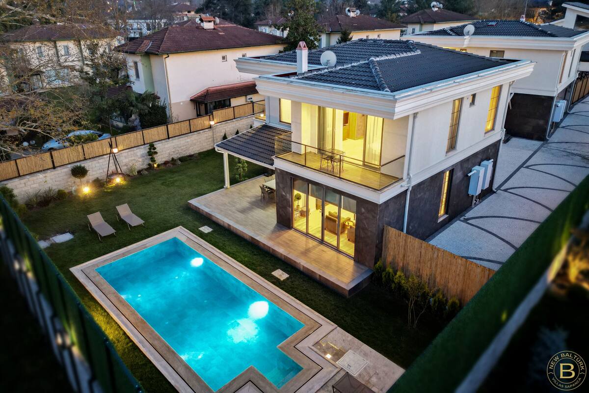 Ein modernes, zweistöckiges Haus mit Swimmingpool, Balkon und einem gepflegten Garten.