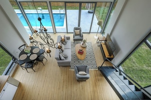 A modern living room with a pool view, a staircase, and a dining area.