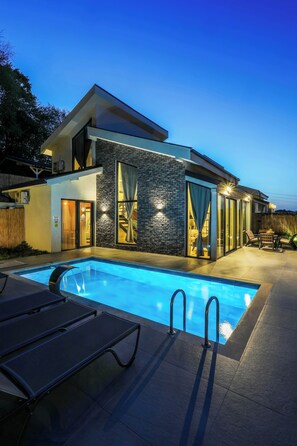 Une maison moderne dotée d’une piscine, d’un espace salon extérieur et d’un escalier menant à l’étage supérieur.