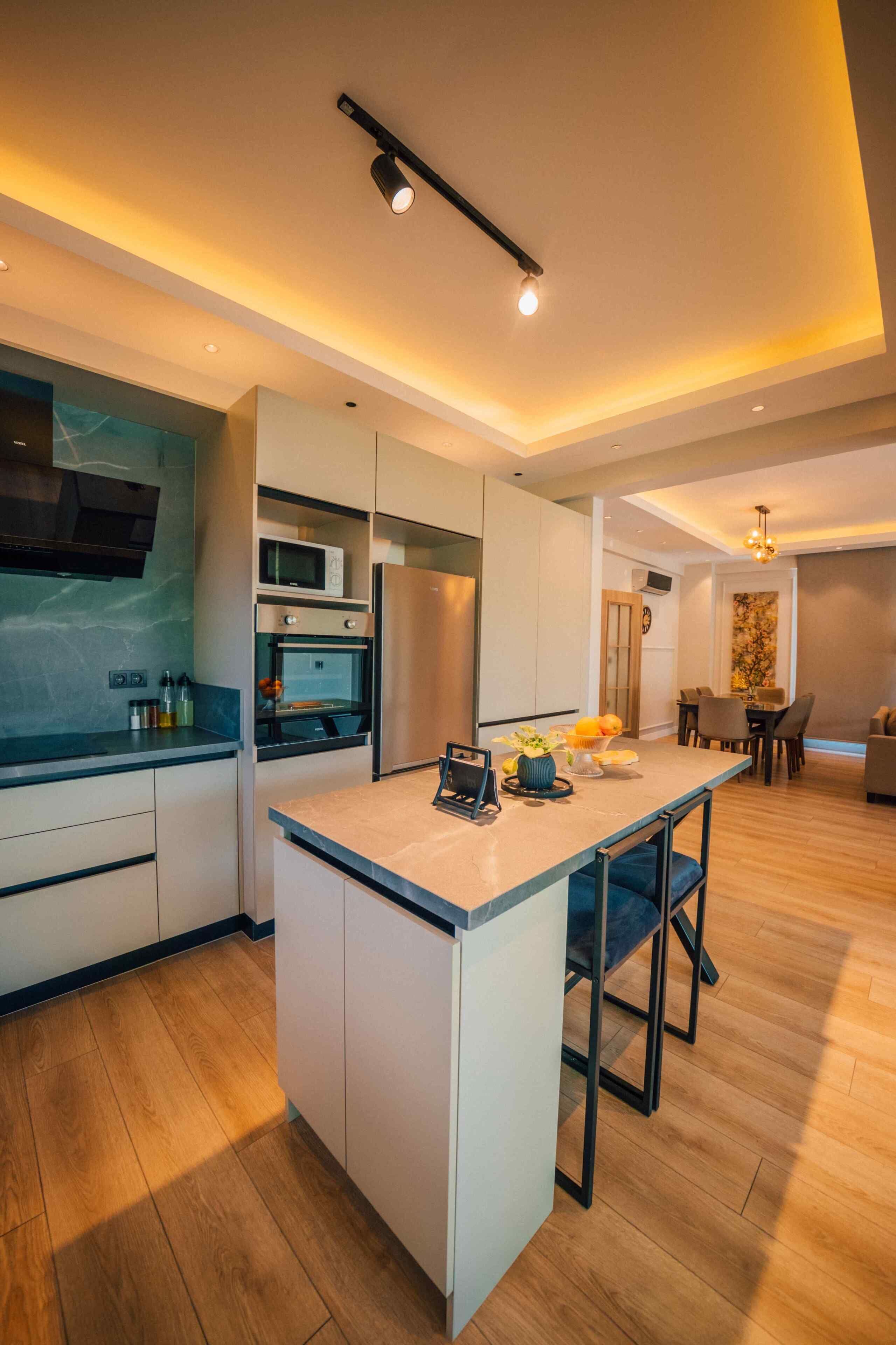 A modern kitchen with built-in appliances, a central island, and a dining area with a table and chairs.