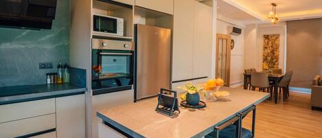 A modern kitchen with built-in appliances, a central island, and a dining area with a table and chairs.
