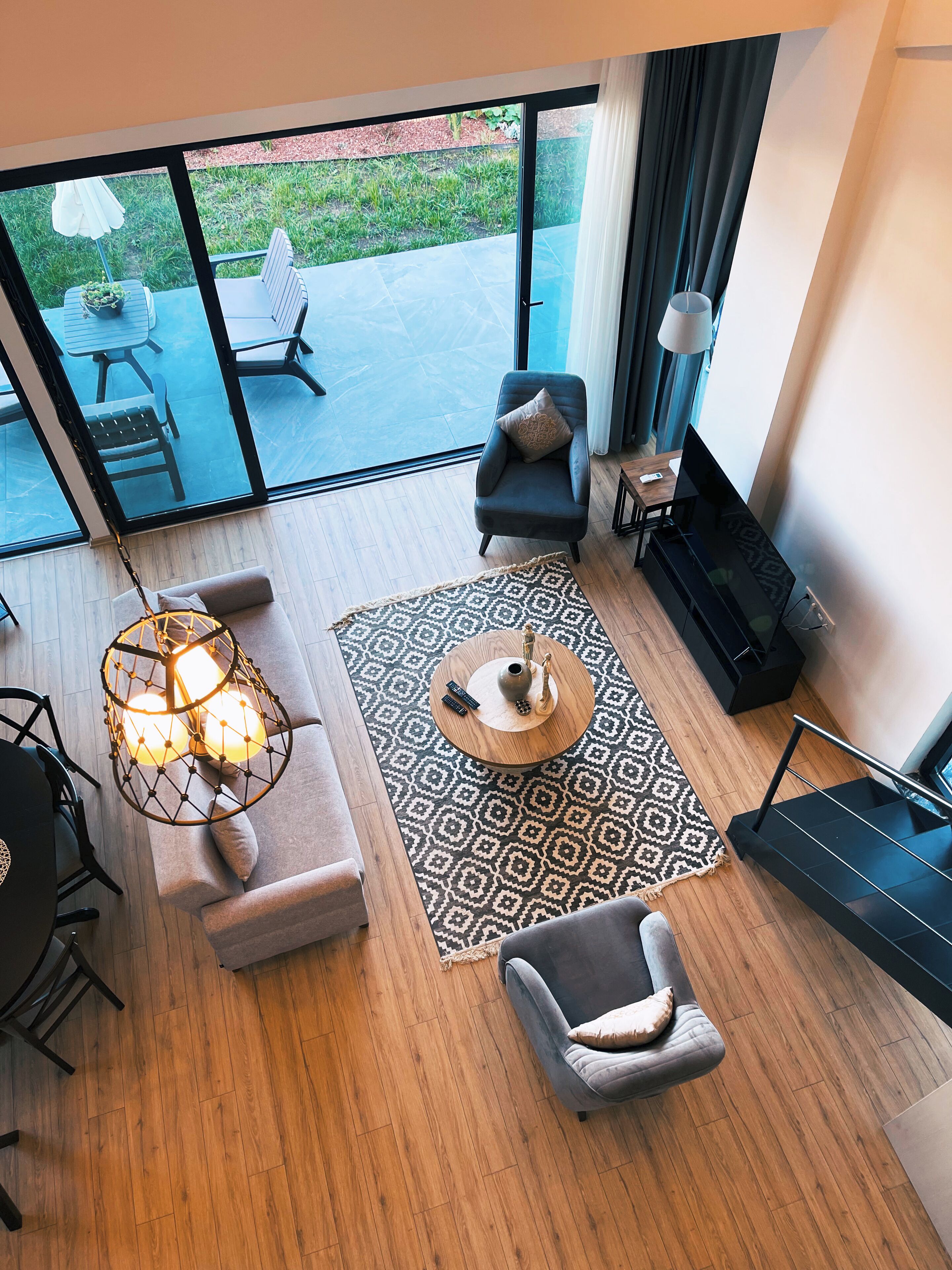 Un salon moderne doté d’une grande porte vitrée donnant sur une terrasse, d’un canapé, d’une table basse et d’une cheminée.